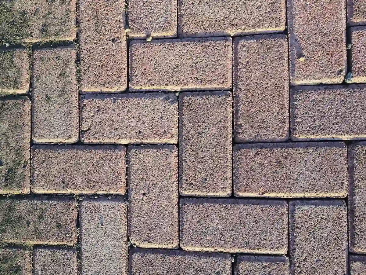 Can You Paint Paving Bricks? What Works and What Peels 1 Close-up of brick-format paving with the colour worn chalky and patchy, and pale sand packed into every joint