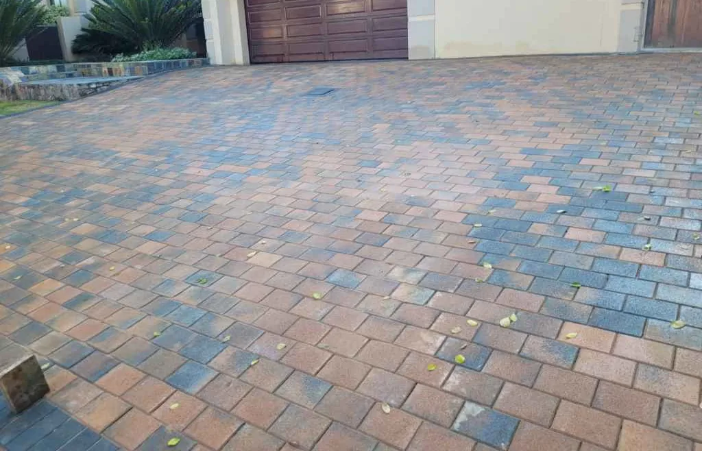 Types of Paving Bricks in South Africa 3 Residential driveway paving laid in stretcher bond, warm sand-toned brick-format units interleaved with darker slate-grey units, joints swept and the surface finished